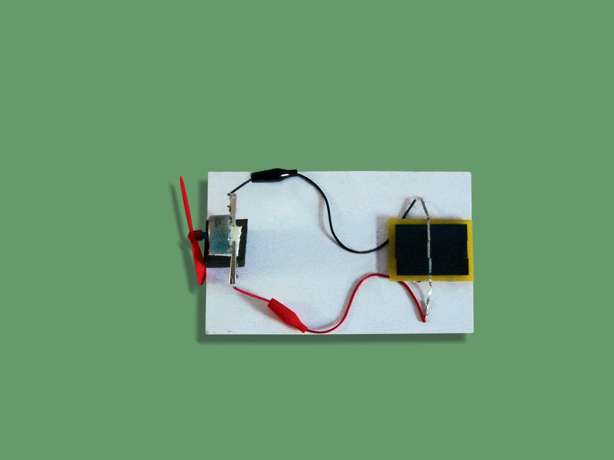 Solar fan kit: solar panel wired to a motor with a red fan on a white board