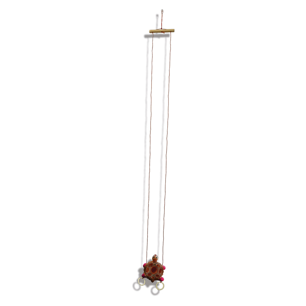 Climbing tortoise hanging from its wooden bar on two strings